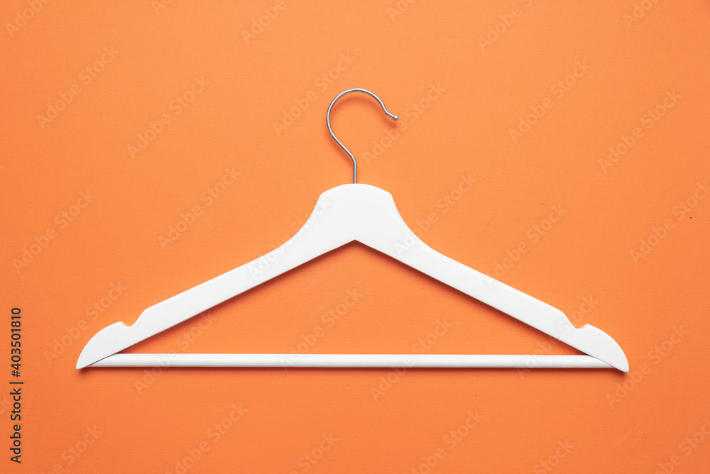 White clothes hanger on the orange flat lay background. White clothes hanger on the orange flat lay background.