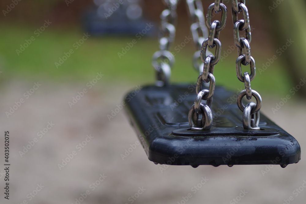 Shallow focus shot of a black swing with silver chains Shallow focus shot of a black swing with silver chains