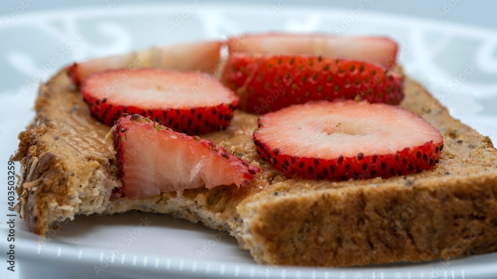 Taking bites off a slice of bread with peanut butter and strawberries Taking bites off a slice of bread with peanut butter and strawberries