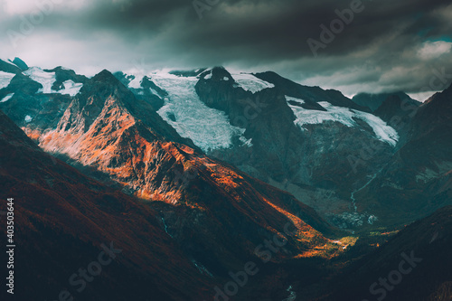 Mountain range with clouds at sunset in Dombay, North Caucasus, Russia. Snow on the mountain peaks. Beautiful autumn landscape.