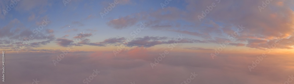 Sunrise panorama in lilac and pale pink shades with cirrus clouds. Sky background. View from the plane during the flight on vacation