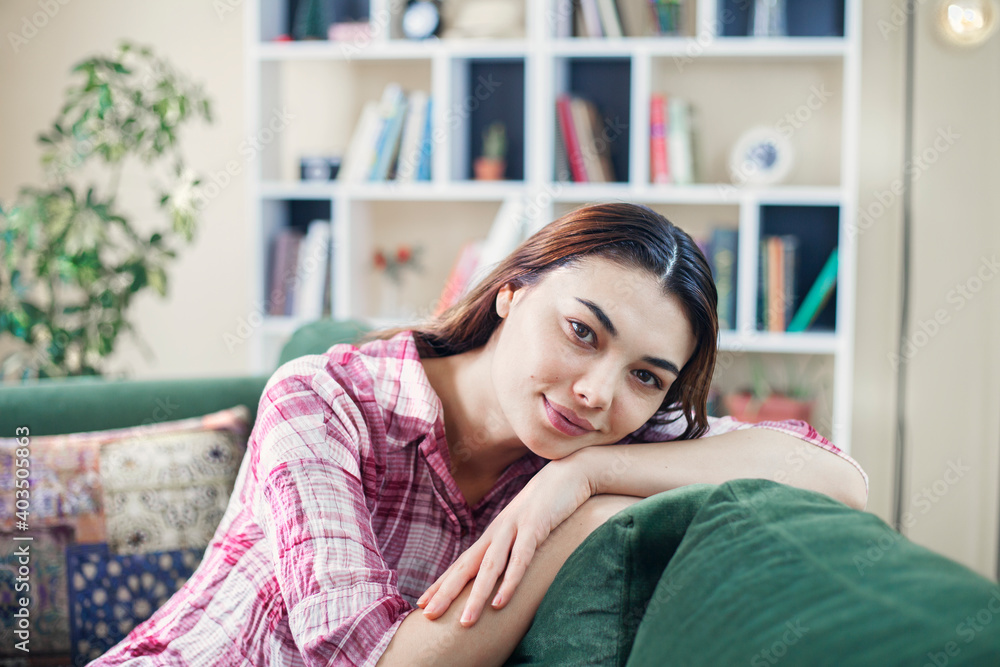 Happy young woman lying on couch and relaxing at home, casual style indoor shoot Happy young woman lying on couch and relaxing at home, casual style indoor shoot