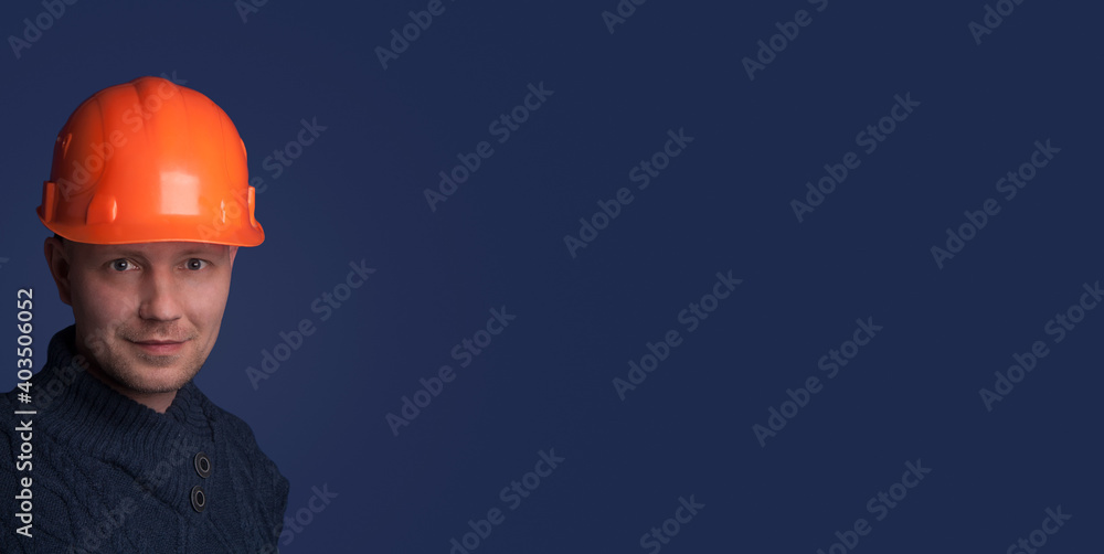 Portrait with copy space, empty place of virile stylish investor with stubble in orange safety helmet, isolated on blue background. Successful confident man engineer. Portrait with copy space, empty place of virile stylish investor with stubble in orange safety helmet, isolated on blue background. Successful confident man engineer.