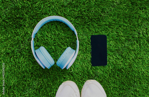 Close up sneakers with wireless headphones and phone on a grass background