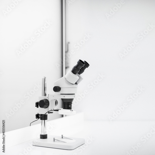 Nowoczesny biały mikroskop stojący na biurku w sterylnym laboratorium