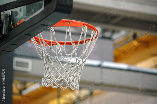 Basketball orange hoop with white net hanging in indoor basketball court