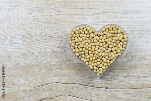 Fresh soybean in a heart shaped mold rests on a wooden table and has a copy space.