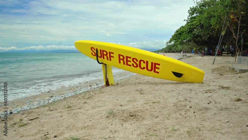 Yellow surfboard on beach with red text surf rescue emergency on a beach Yellow surfboard on beach with red text surf rescue emergency on a beach
