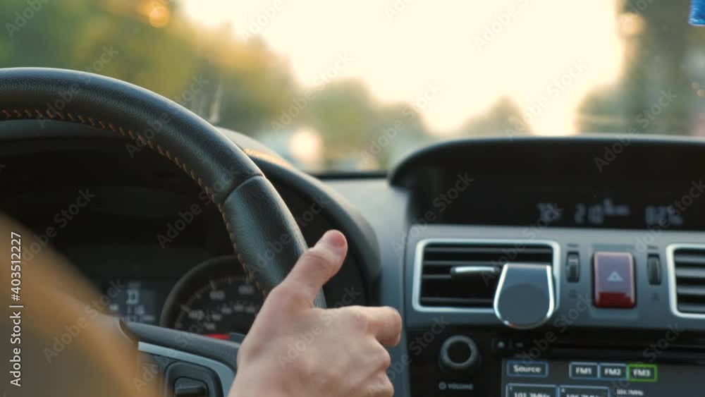 Rear view of female driver behind steering wheel driving a car on a city street. Rear view of female driver behind steering wheel driving a car on a city street.