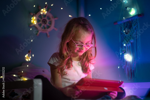  girl with glasses plays with tablet at night