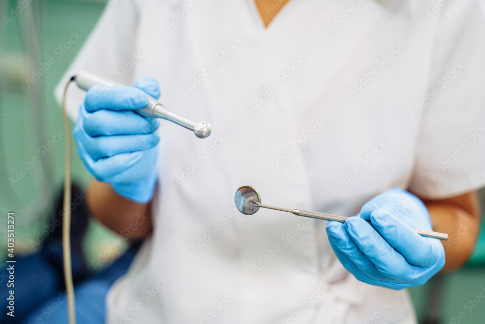 Close-up of the dentist's hands with medical devices. Large detail - dentist's mirror, curling and probe. Resolving dental problems effectively with confident, professional gestures Close-up of the dentist's hands with medical devices. Large detail - dentist's mirror, curling and probe. Resolving dental problems effectively with confident, professional gestures