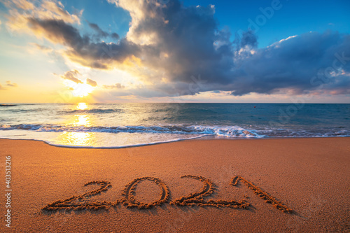 Happy New Year 2021 concept, lettering on the beach. Written text on the sea beach at sunrise.