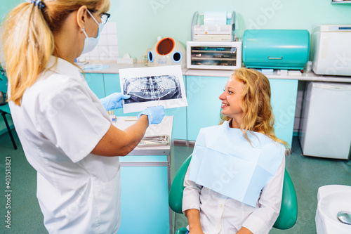 Dentist and the patient examine image of the dental cavity, teeth, in order to choose a treatment in consultation with medical equipment. Correction of bite deficiencies. Deep tooth canal treatment