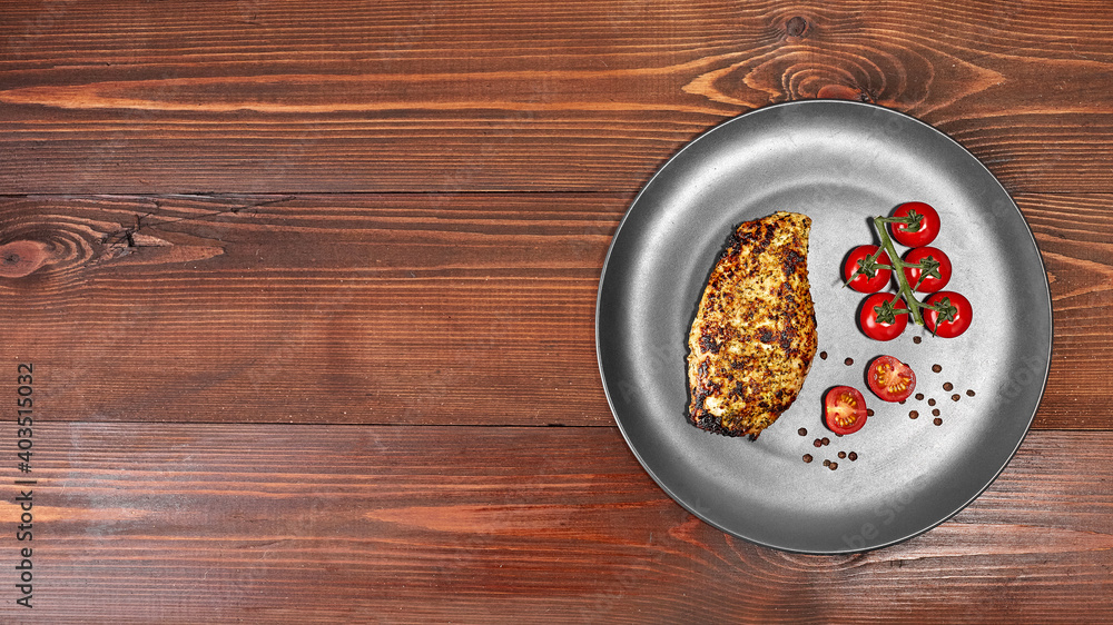 fried chicken fillet on a plate with cherry tomatoes, on a wooden texture. Top view with copy space for text decoration fried chicken fillet on a plate with cherry tomatoes, on a wooden texture. Top view with copy space for text decoration