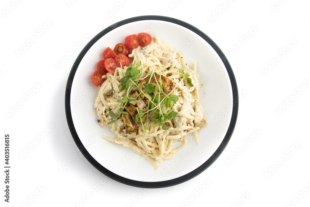 overhead view of of a plate linguini Alfredo with chicken garnished with small tomatoes and pea shoots isolated on white overhead view of of a plate linguini Alfredo with chicken garnished with small tomatoes and pea shoots isolated on white