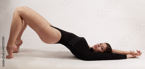 Young woman with athletic body lies on her back doing exercises