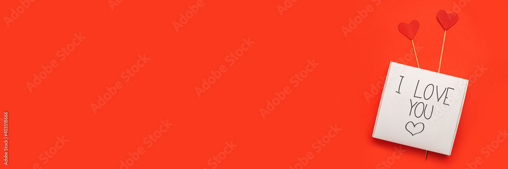 Gift box with the text Love and hearts on a stick on a red background. Composition Valentine's Day. Banner. Flat lay, top view Gift box with the text Love and hearts on a stick on a red background. Composition Valentine's Day. Banner. Flat lay, top view