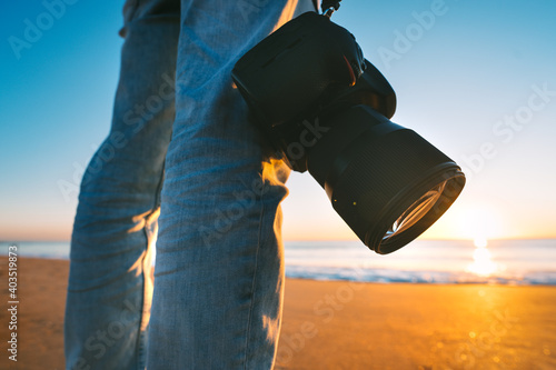 Photographer with his camera on the beach. Sunset photography