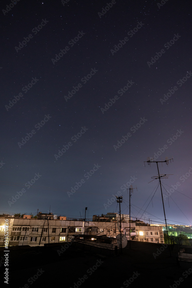 Night starry cityscape with a lot of stars and constellations.
