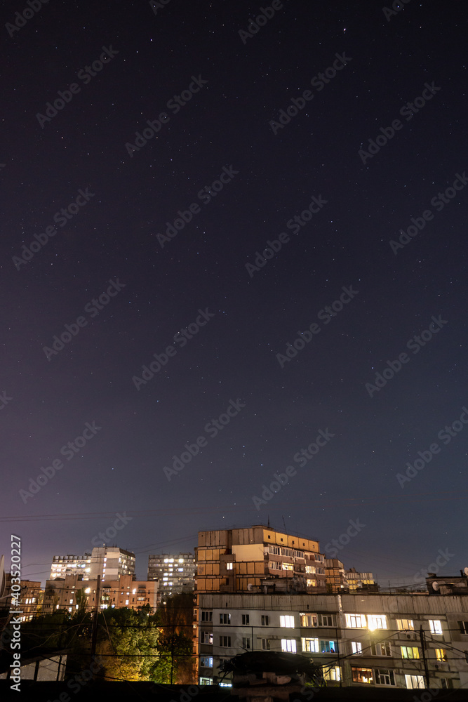 Night starry cityscape with a lot of stars and constellations.
