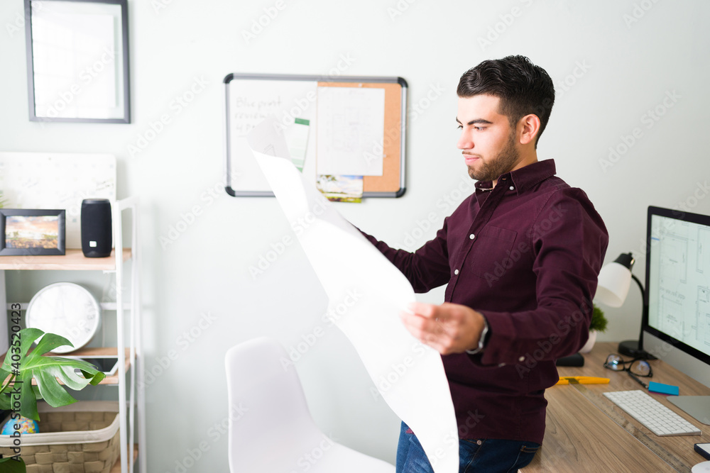 Side view of a man checking the blueprint of a new construction Side view of a man checking the blueprint of a new construction