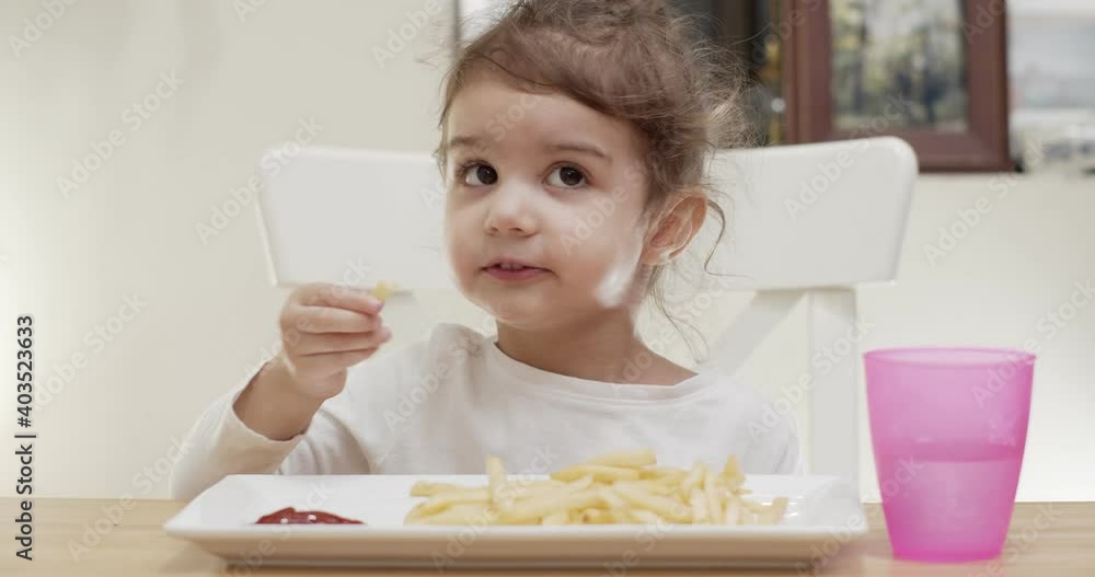 Cute toddler girl eating french fries. Cinematic 4K footage. Cute toddler girl eating french fries. Cinematic 4K footage.