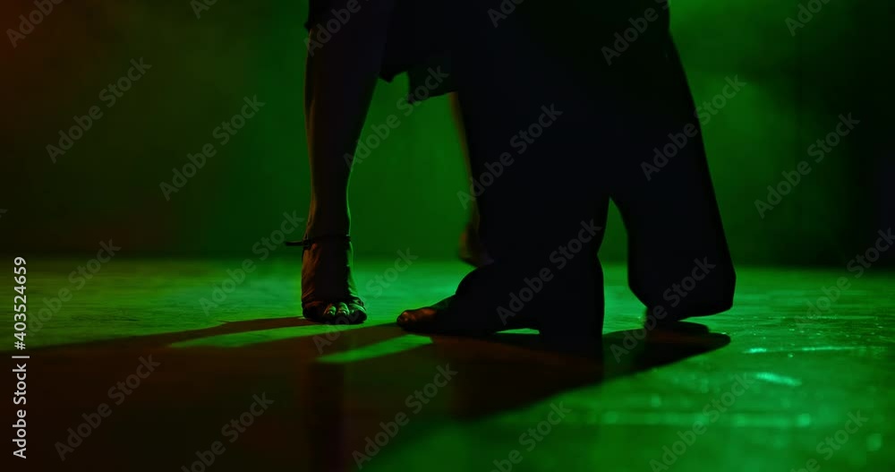Silhouette of the legs of a man and a woman dancing in a dark studio with a green spotlight, beautiful movements of the legs, tango. Legs of a man and a woman move in a dance, close-up. 4k, ProRes Silhouette of the legs of a man and a woman dancing in a dark studio with a green spotlight, beautiful movements of the legs, tango. Legs of a man and a woman move in a dance, close-up. 4k, ProRes