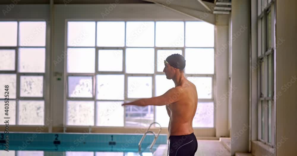 Amputee professional athlete doing arms stretches in indoor pool Amputee professional athlete doing arms stretches in indoor pool