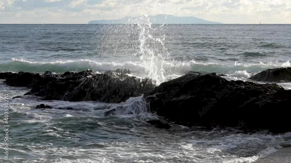 海岸の岩で砕ける波と遠くに見える伊豆大島 海岸の岩で砕ける波と遠くに見える伊豆大島