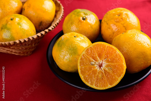 Tangerine orange fruit on black plate with red background, Chinese New Year concept