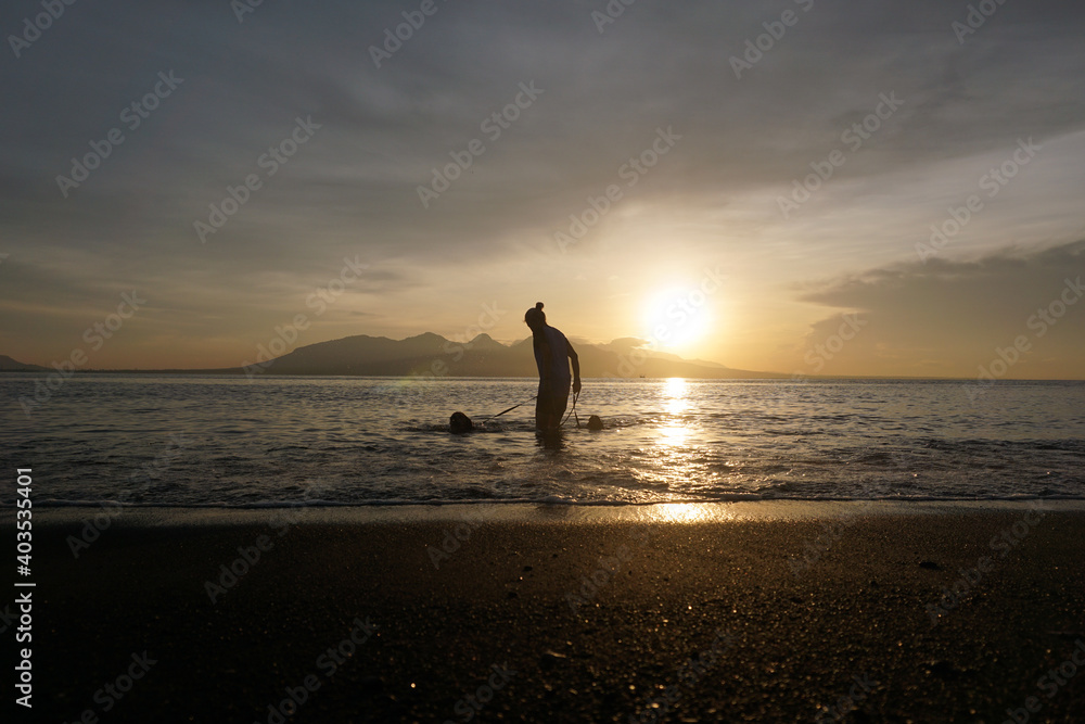 A woman playing with puppies at the beach. The weather so clear and beautiful.