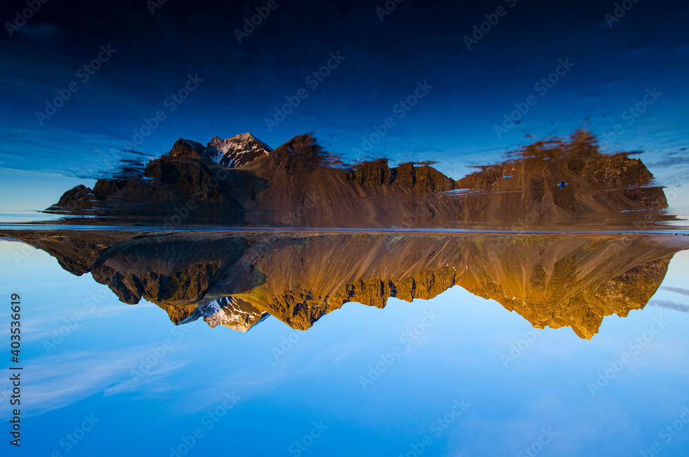Jagged Vestrahorn Mountain in Iceland during winter with clear sky.  Photo is upside down with reletion in iced over beach.