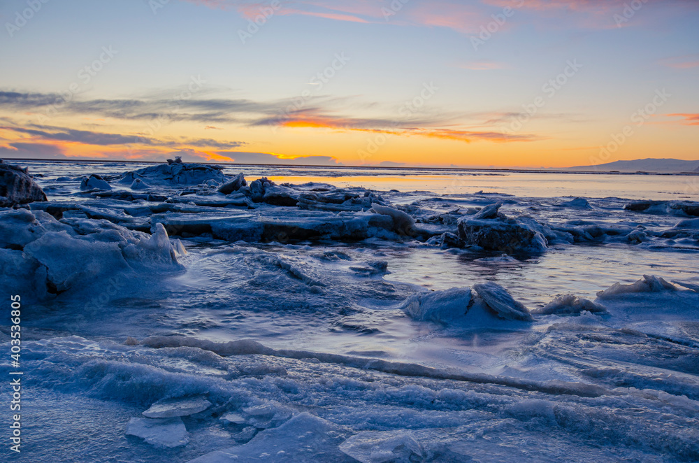 Sunset over the ocean and cracked ice field, on a winter day in Iceland.