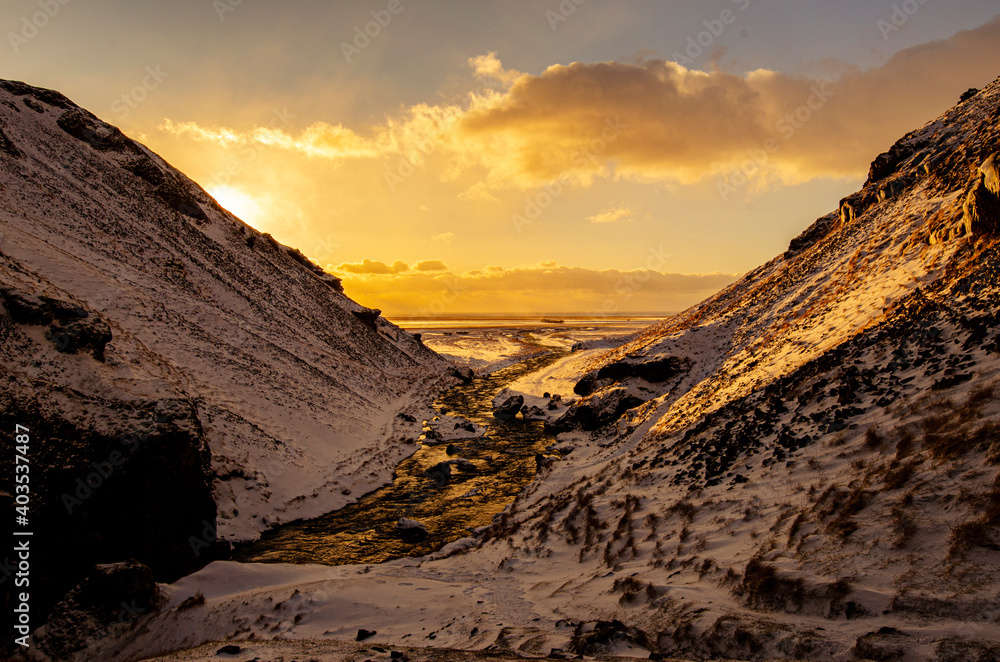 Sunsetting behind snow-covered hills, with the winding river leading to the horizon.  