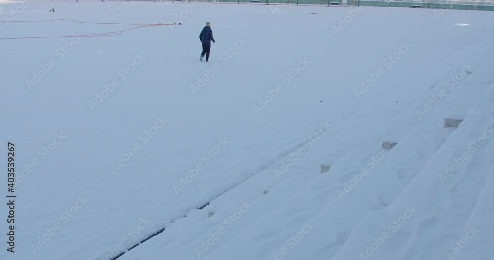 a man jogging in a snow-covered playground. a man jogging in a snow-covered playground.