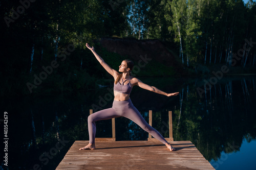 Beautiful young woman performing a spiritual yoga pose on a forest lake at sunny day  sunrise zen wellness