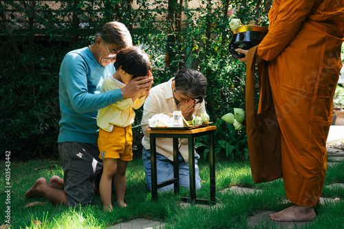 Family give alms offering and pay respect to buddhist monk in the morning.