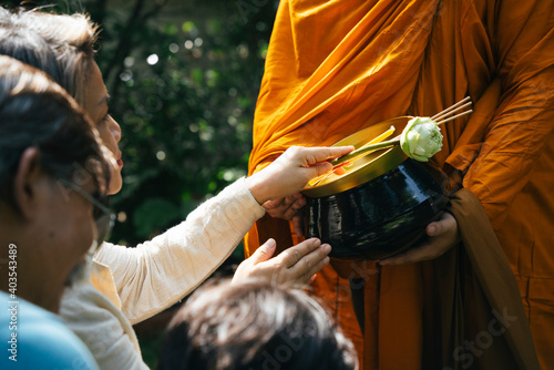 Fotografia People giving alms offering with lotus and incense to monk in the morning