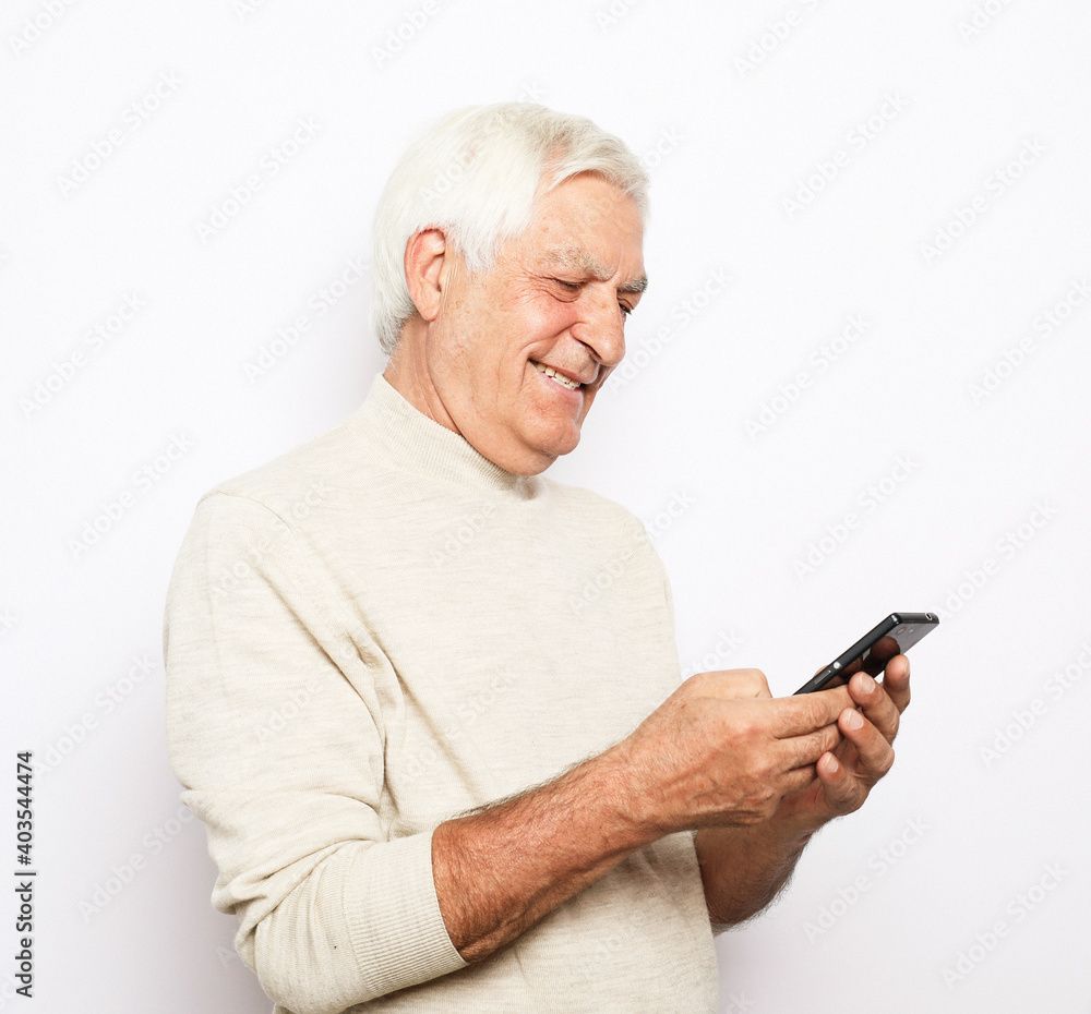 Tehnology and old people concept: Portrait of senior man who is messaging on smartphone over white background Tehnology and old people concept: Portrait of senior man who is messaging on smartphone over white background