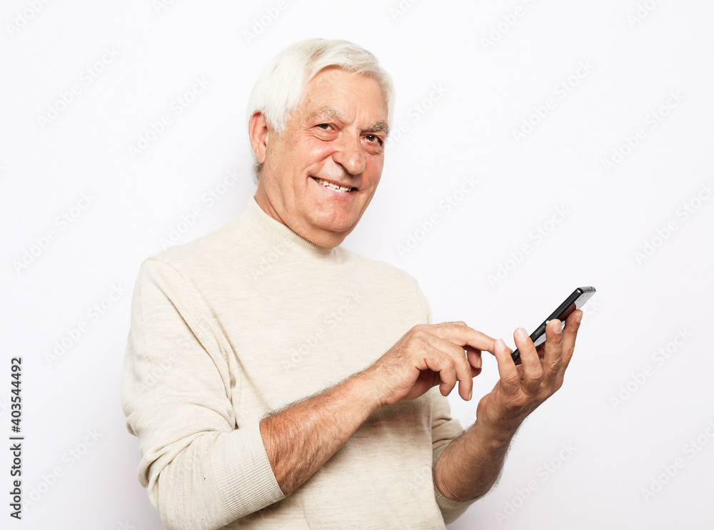 Tehnology and old people concept: Portrait of senior man who is messaging on smartphone over white background Tehnology and old people concept: Portrait of senior man who is messaging on smartphone over white background