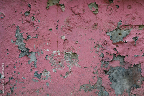 Close-up peeling plaster of color on cement wall. Pink background.