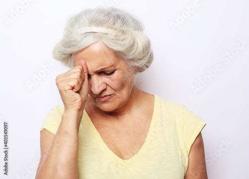 Lifestyle, health and old people concept: Elderly female touching her head having a headache