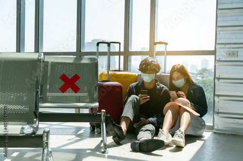 Couple in airport using travel app on smart phone while waiting for boarding in the airport.