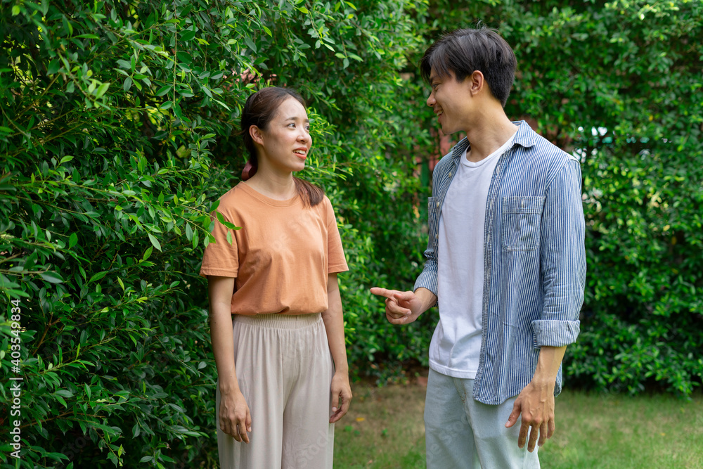 Young asian couple talking to each other at yard. Young asian couple talking to each other at yard.