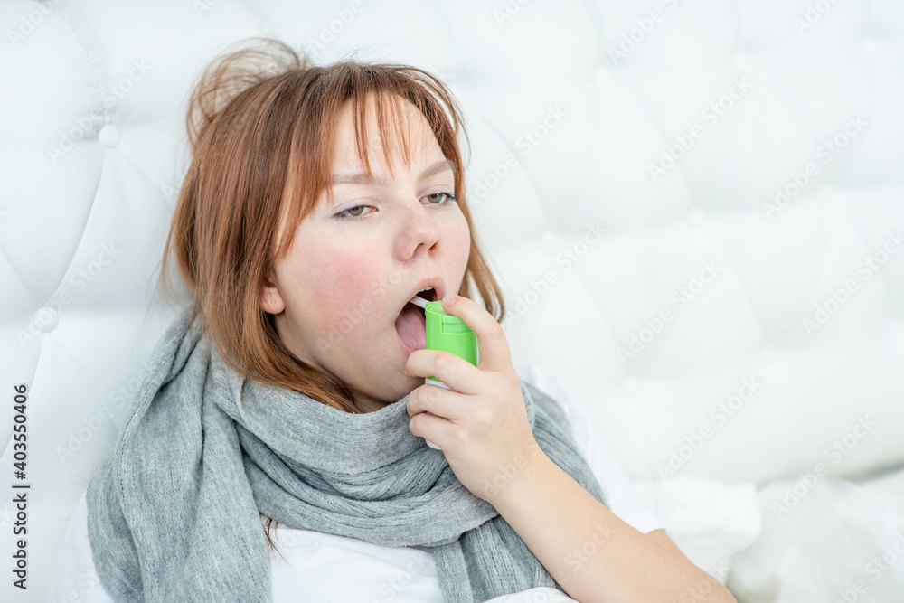 Teen girl spraying in her mouth with a spray from the pain in her throat. Empty space for text Teen girl spraying in her mouth with a spray from the pain in her throat. Empty space for text