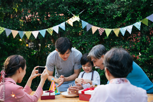 Asian kid celebrate birthday party with family outdoors.