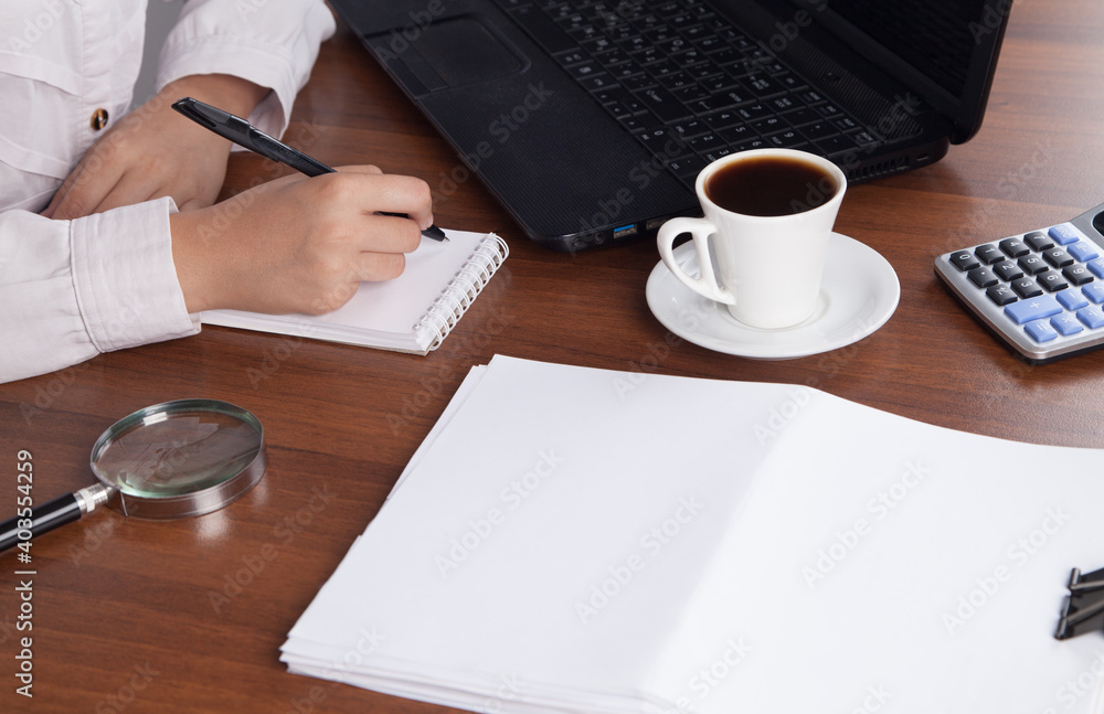 Young businesswoman working in an office with a cup of coffee.