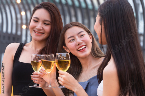asian woman teenagers cheering and toast with white sparkling wine glass to celebrating at dinner party in summertime. celebration, relationship and friendship concept.