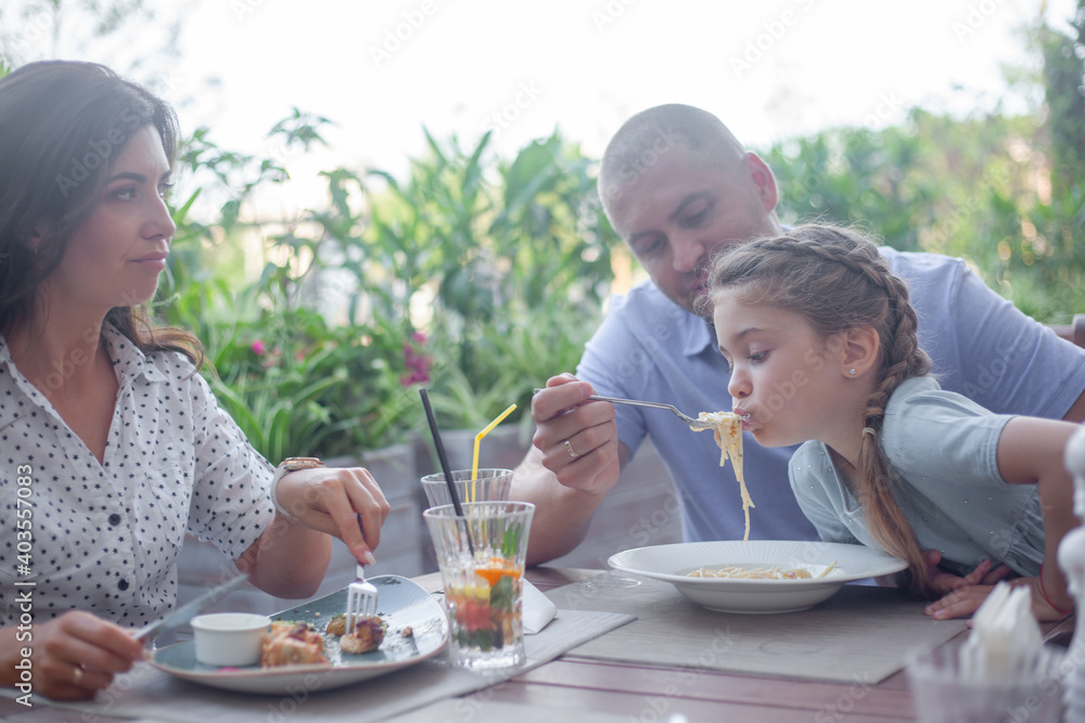 Happy family, mother father and kid eating pasta in cafe Happy family, mother father and kid eating pasta in cafe