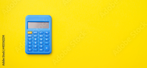 Blue calculator on yellow background photo